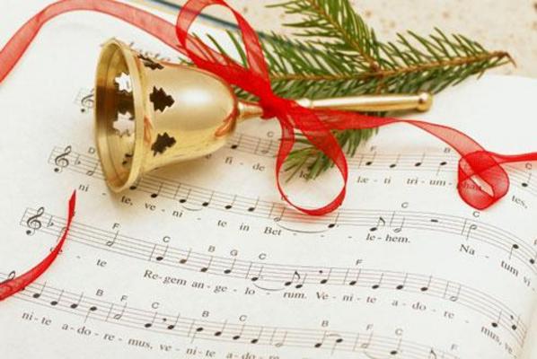 Sheet music with a bell, red ribbon and piece of pine tree on top